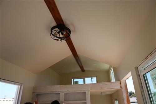 Finishing touches added to the ceiling with a wood beam stretching the length of the home and fan added.